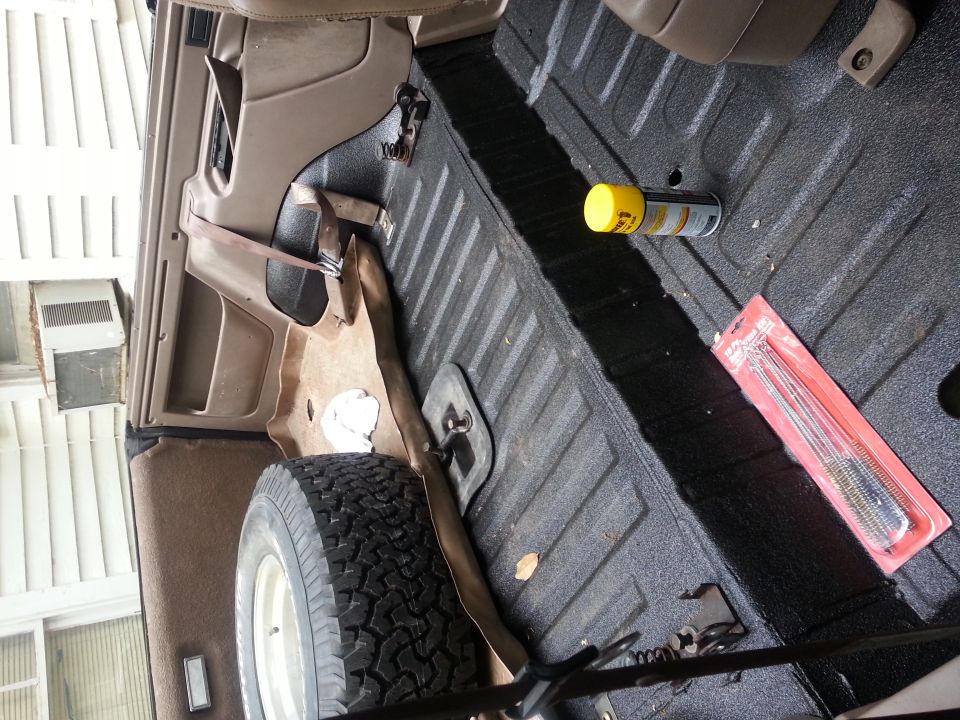 spare tire, spray can, and cleaning brushes in cargo area of a vehicle