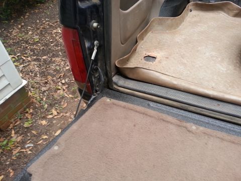 1995 Ford Bronco - The rear cargo area of a 1995 Ford Bronco is shown with the tailgate down and a tan floor mat visible.