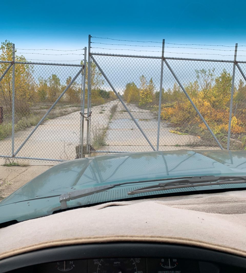 View from inside a vehicle looking through a gate at a road.