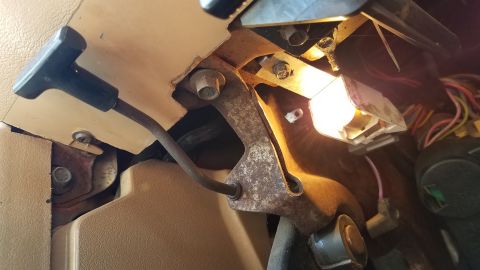 1985 Ford Bronco - A close-up view of the interior of a vehicle, focusing on the driver's side footwell area. Visible components include the parking brake lev…