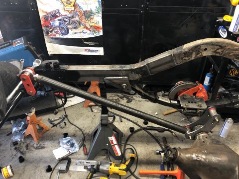 1992 Jeep Wrangler - A Jeep Wrangler frame is being worked on in a garage setting. The frame is supported by jack stands, and various tools and parts are scatte…
