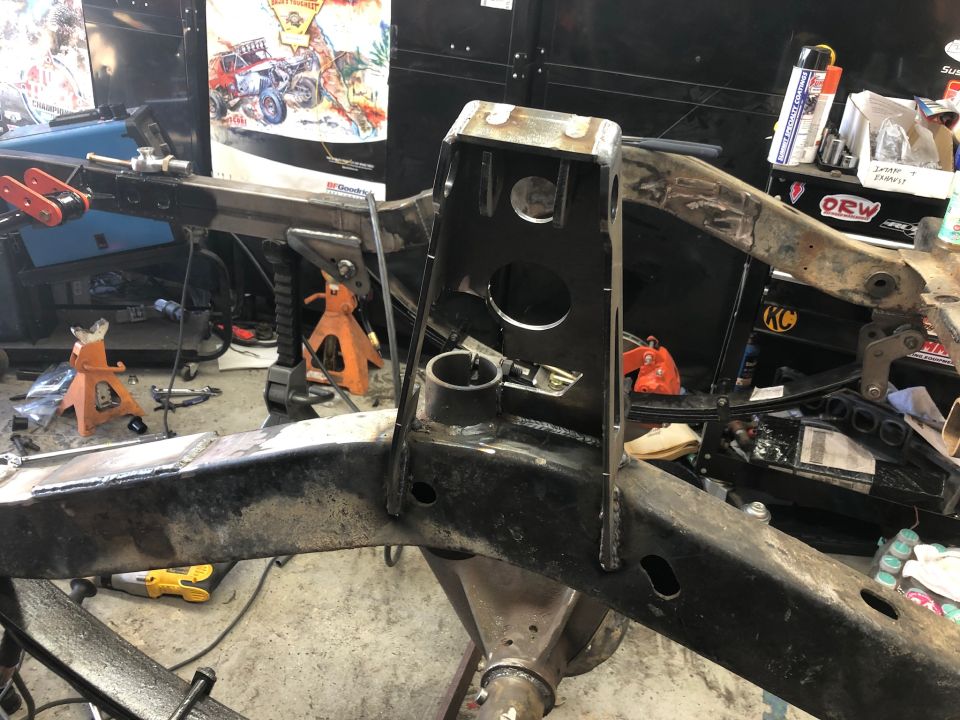 Modified Jeep Wrangler frame with welded reinforcements and suspension parts in a workshop.