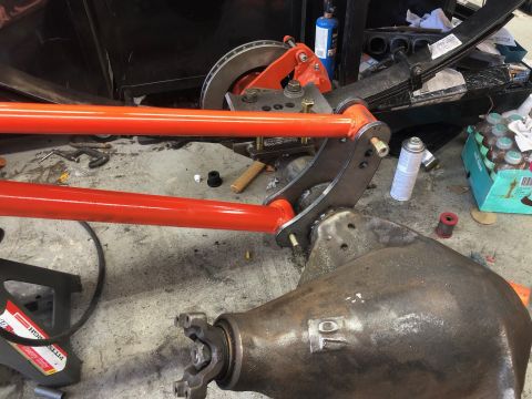 1992 Jeep Wrangler - A close-up view shows the rear axle assembly of a vehicle under construction, featuring bright orange suspension control arms, a leaf sprin…