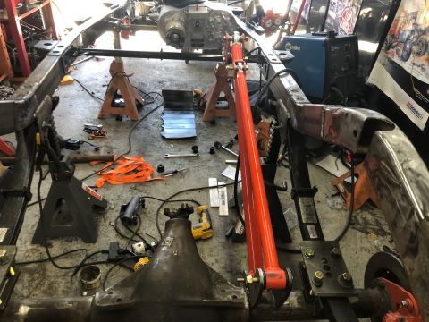 1992 Jeep Wrangler - A Jeep Wrangler frame is supported by jack stands with various tools and parts scattered around the garage floor. A blue Miller welding mac…