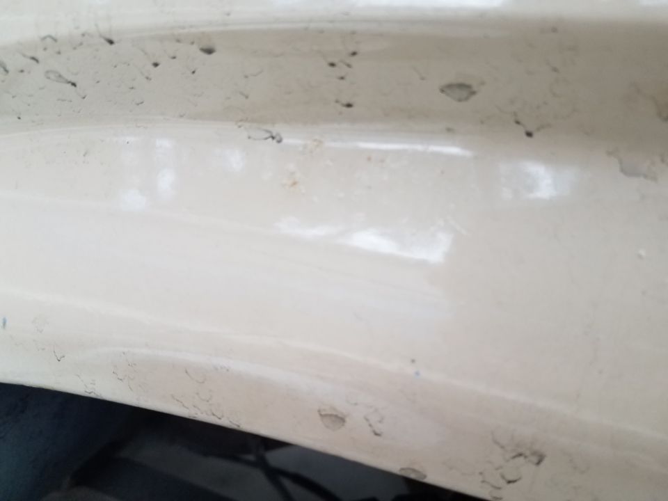 Close-up of chipped cream exterior paint on a vehicle.