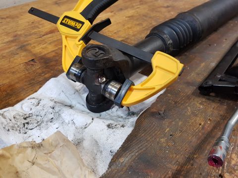 1978 Ford Bronco - A close-up shot shows a universal joint on a driveshaft being held in place by a yellow DeWalt clamp. The driveshaft and universal joint ar…