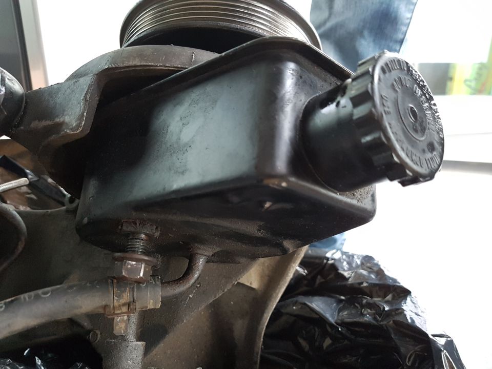 Black power steering pump reservoir with pulley and hose clamp