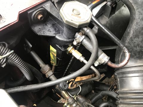 1994 Ford Bronco - A close-up view of the power steering fluid reservoir and hoses in a vehicle's engine bay. The reservoir is black with a yellow label, and…