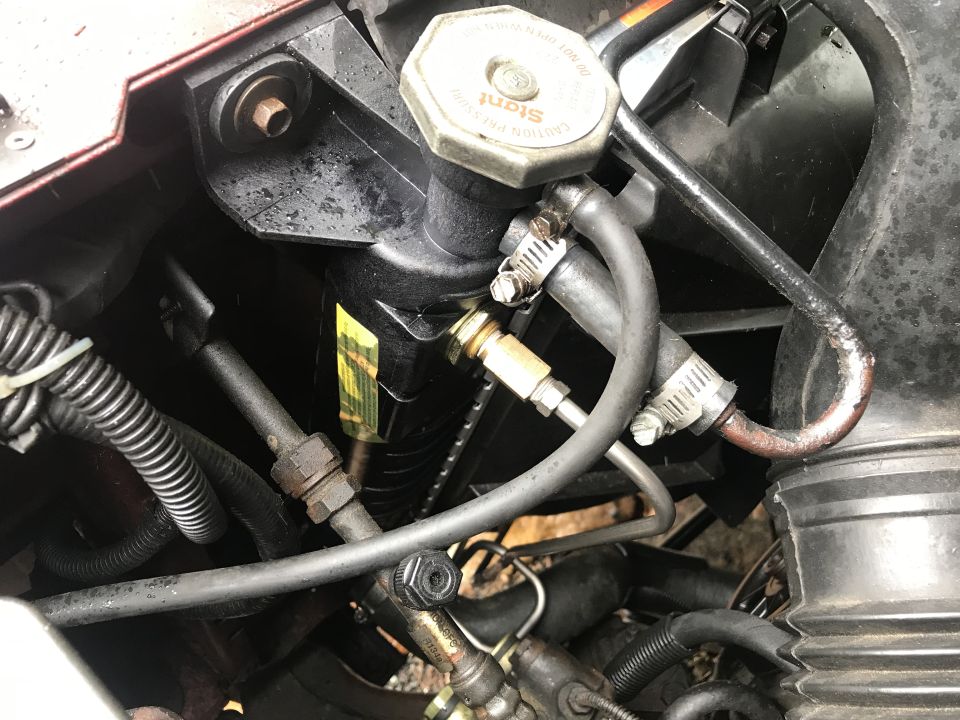 Close-up of power steering reservoir and hoses in engine bay.