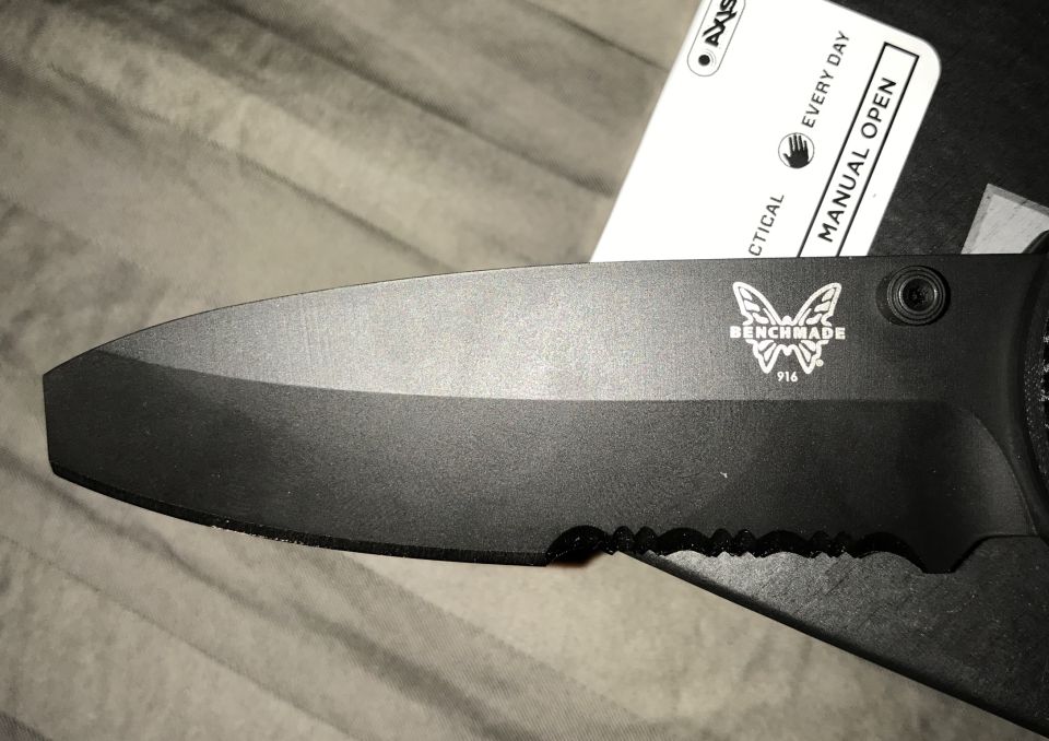 Black Benchmade knife with serrated edge and model 916, with a card behind it.