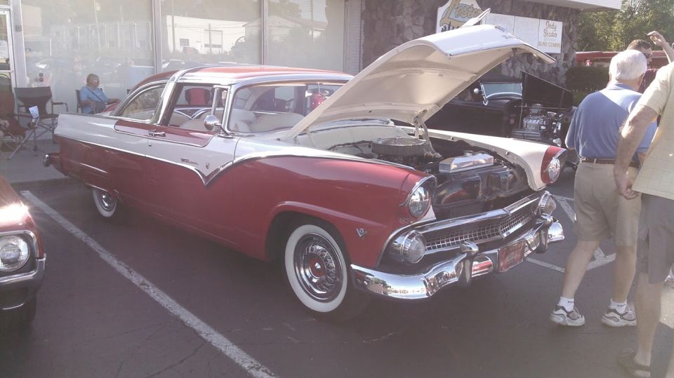 1950s red and white classic car with hood open, parked.