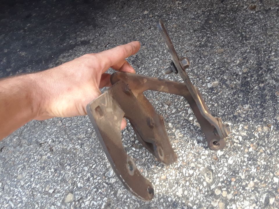 Two rusty metal brackets with bolts held by a hand.