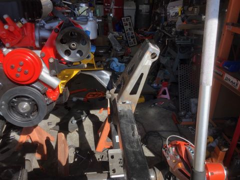 1992 Jeep Wrangler - A red and silver engine is mounted on orange jack stands in a cluttered garage. A custom metal fabrication is attached to the engine assemb…
