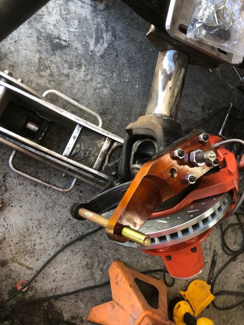 1992 Jeep Wrangler - A close-up view of a vehicle's brake caliper and rotor assembly, possibly during a repair or modification. The assembly is orange and red,…