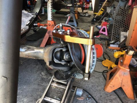 1992 Jeep Wrangler - A close-up view of a vehicle's front axle assembly, likely a Jeep Wrangler, undergoing modification or repair. A specialized tool is clampe…