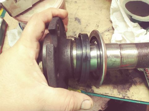 1996 Ford Bronco - A person's hand holds a vehicle wheel hub assembly with visible seals and a threaded axle shaft.