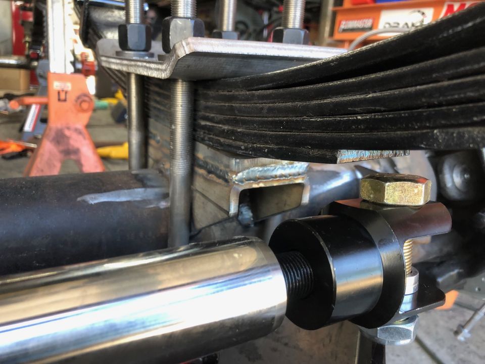 Close-up of custom leaf spring suspension with fabricated bracket and linkage.