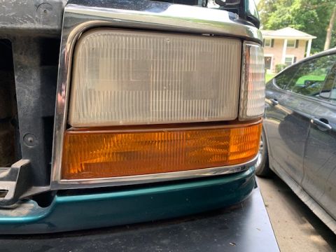 1996 Ford Bronco - The front corner of a dark green Ford truck, showing the headlight and turn signal assembly.