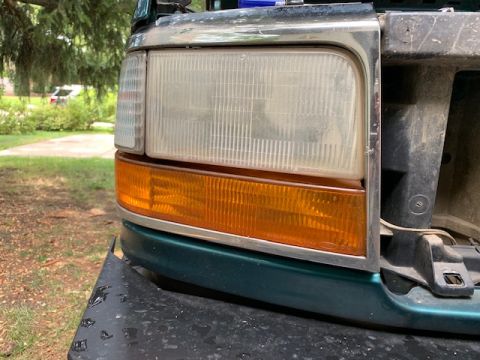 1996 Ford Bronco - Close-up of the front corner of a green Ford Bronco, showing the headlight and turn signal assembly.