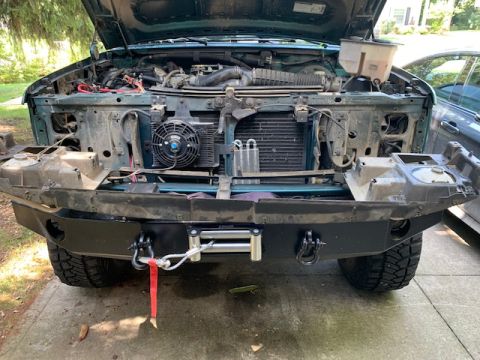 1996 Ford Bronco - Front end of a green 1996 Ford Bronco disassembled, revealing the engine and a winch bumper.