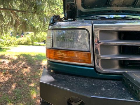 1996 Ford Bronco - Close-up of a green Ford truck's front end, revealing its grille and headlight assembly.