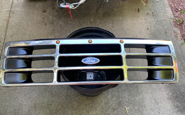 Chrome and black Ford Bronco grille with amber marker lights and Ford logo.