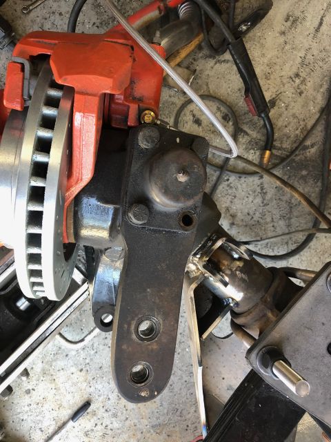 1992 Jeep Wrangler - A close-up view of a vehicle's suspension and braking system, featuring an orange brake caliper, a drilled brake rotor, and various metal c…