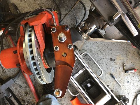 1992 Jeep Wrangler - A close-up view of an orange brake caliper and rotor assembly attached to a suspension component, likely part of a vehicle modification or…