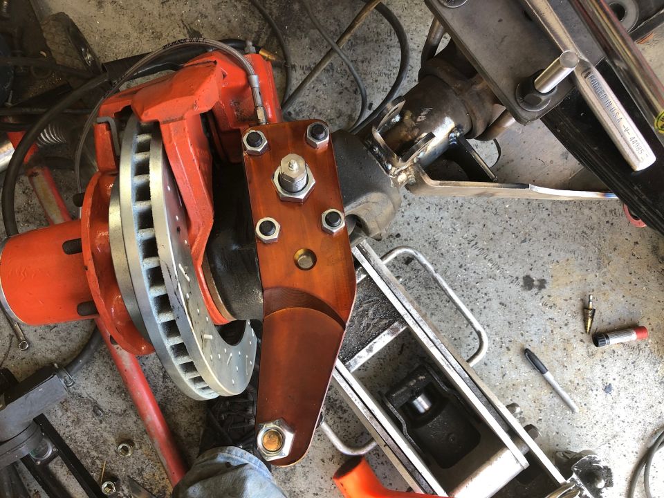 Orange brake caliper and rotor assembly on a vehicle suspension component.