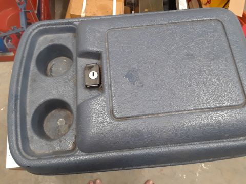 1994 Ford Bronco - A gray plastic center console with two cup holders and a locking lid is shown. A small key lock is visible on the console.