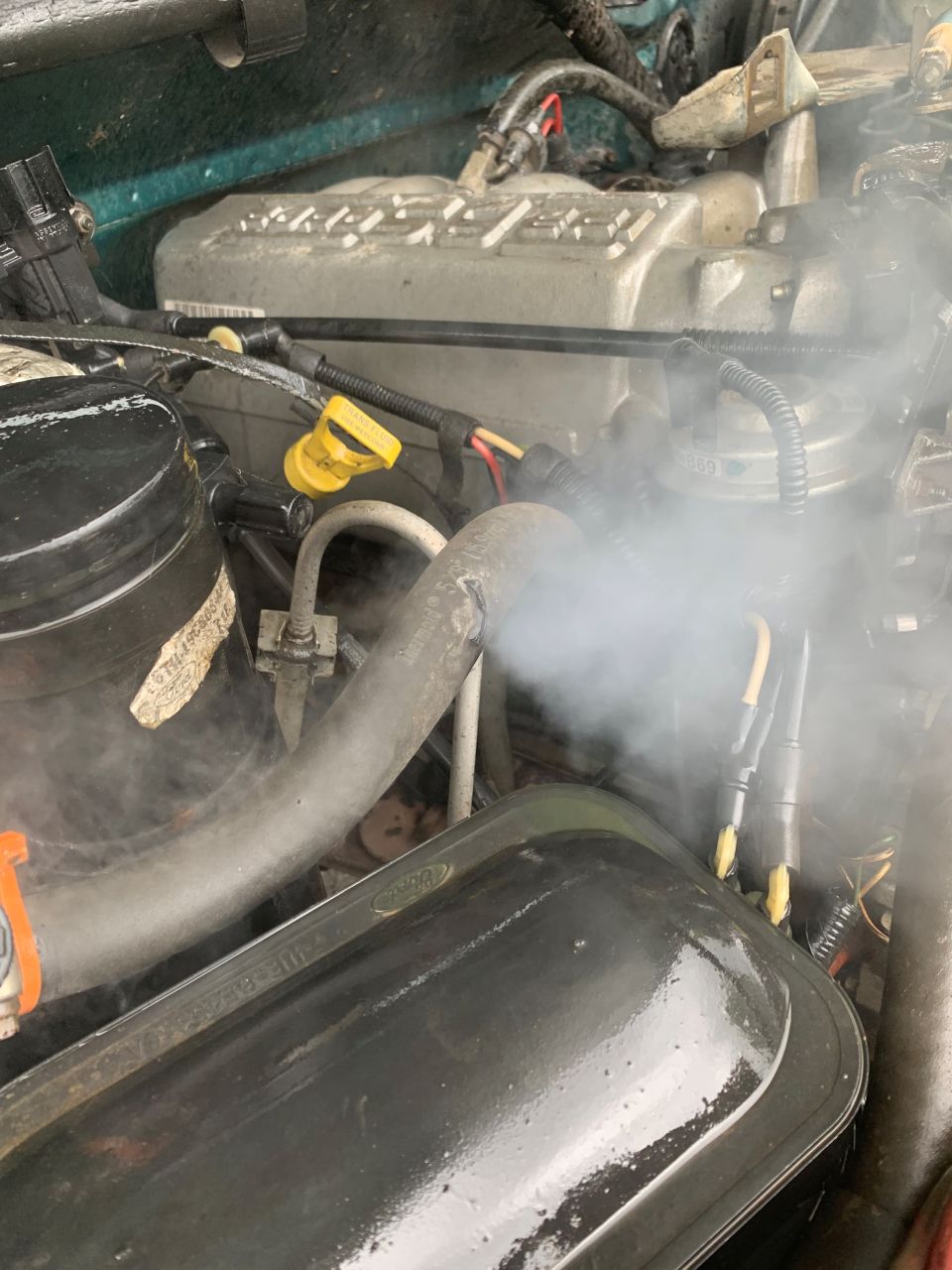 Steam escaping from a hose in the engine bay of a 1996 Ford Bronco.