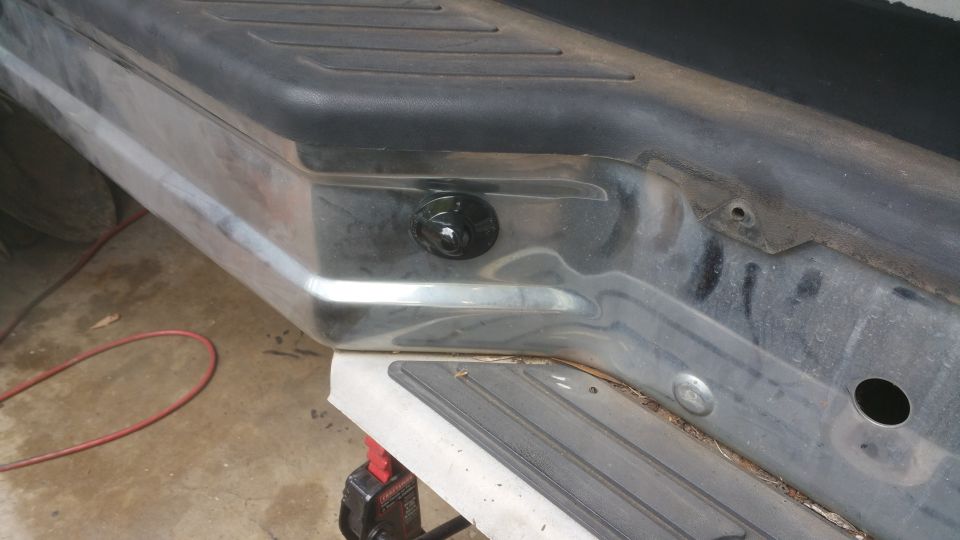 Close-up of a black knob on a chrome rear bumper of a vehicle.