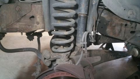 1996 Ford Bronco - This image shows the front suspension system of a vehicle, including the coil spring and shock absorber.
