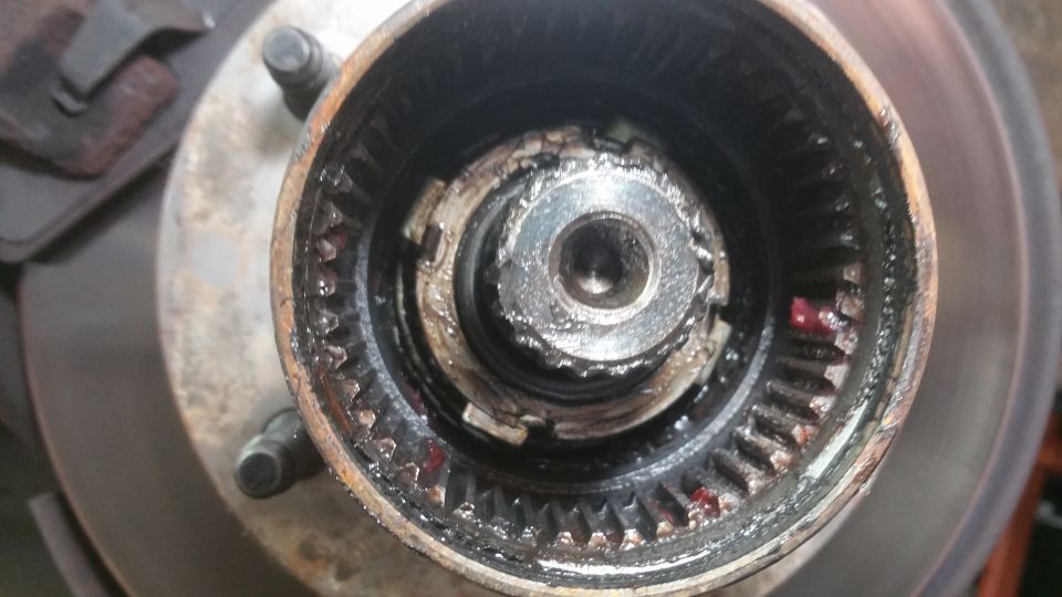 close-up of a rusty wheel hub assembly with visible gears and grease