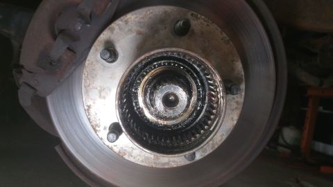 1996 Ford Bronco - Close-up of a rusty front wheel hub assembly with a brake rotor and caliper.