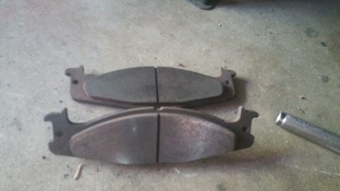 1996 Ford Bronco - Two brake pads are shown on a concrete surface, with a metal rod to the right. The registry claims they are from a 1996 Ford Bronco.