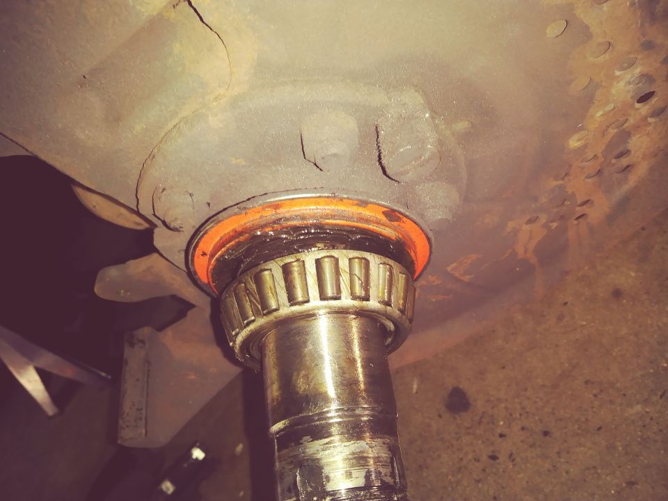 Close-up of a wheel bearing and spindle assembly with an orange seal