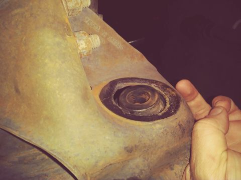 1996 Ford Bronco - A close-up view of a corroded vehicle suspension component, showing bolts and a worn bushing.