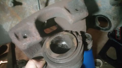 1996 Ford Bronco - A close-up view of a rusty brake caliper, likely needing replacement or repair.
