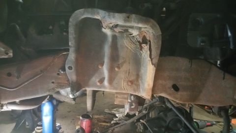1996 Ford Bronco - The photo shows the rusty undercarriage of a vehicle, focusing on the frame and suspension components.