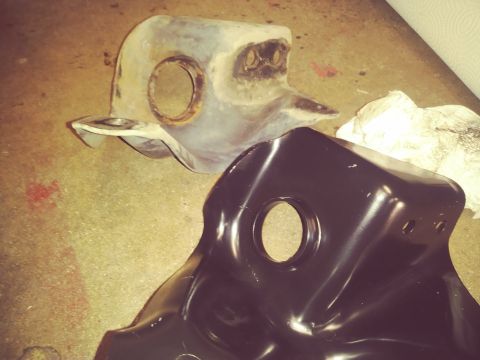 1996 Ford Bronco - Two automotive suspension parts, one showing rust and the other freshly painted black, are displayed on a floor.
