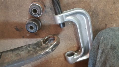 1996 Ford Bronco - A ball joint separator tool is shown with old suspension bushings and a control arm, likely for a vehicle repair.