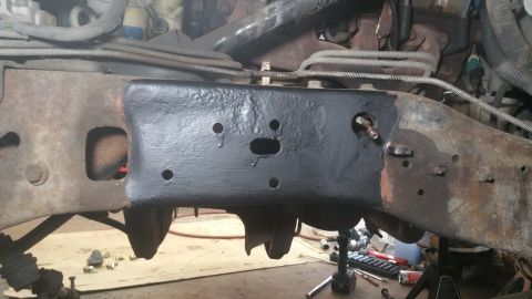 1996 Ford Bronco - A section of a vehicle's frame, showing both painted and rusted areas, with visible suspension components.