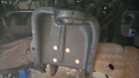 1996 Ford Bronco - Close-up view of a black metal shield, likely part of the front suspension system, with four visible bolts.