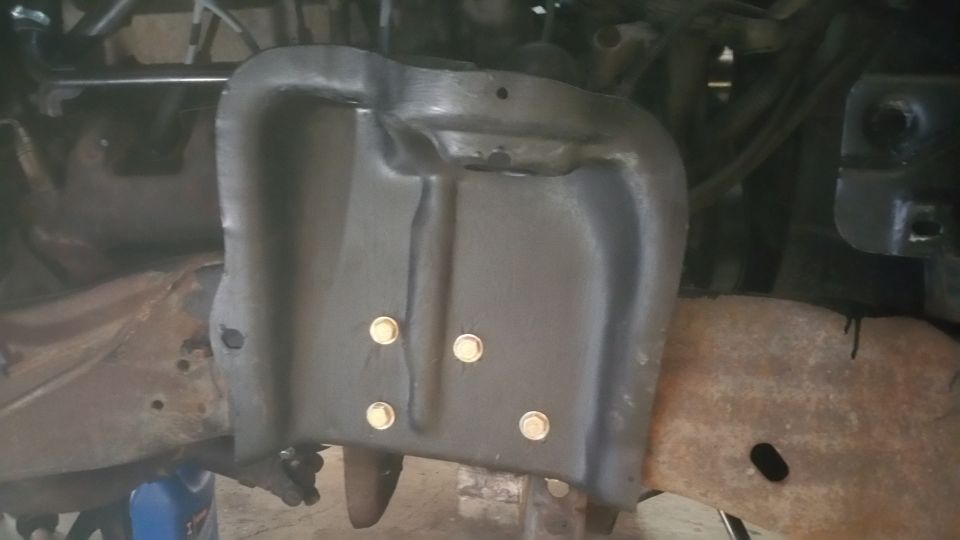 Black metal front suspension shield with four visible bolts