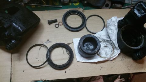 1996 Ford Bronco - Disassembled brake caliper components laid out for service, showing the caliper body, piston, and seals.