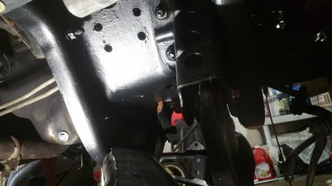 1996 Ford Bronco - Underside view of vehicle chassis components, showing painted metal and suspension linkages.