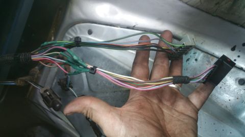 1996 Ford Bronco - A hand holds a bundle of wires and connectors, likely from a vehicle's interior.