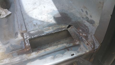 1996 Ford Bronco - Close-up view of a heavily rusted vehicle floor pan, showing cutouts and signs of wear.