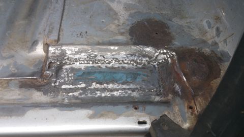 1996 Ford Bronco - Close-up of a corroded vehicle floor pan showing areas of repair and rust.